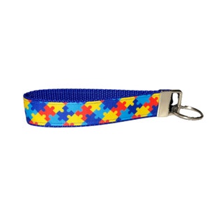 May include: Blue, red, yellow, and light blue puzzle piece patterned key chain with a silver key ring.
