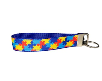 May include: Blue, red, yellow, and light blue puzzle piece patterned key chain with a silver key ring.