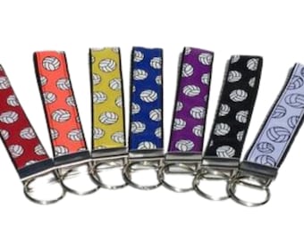 May include: Set of eight volleyball keychains with different colored backgrounds. Each keychain features a white volleyball design.