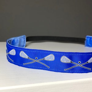 A blue nonslip headband with white lacrosse sticks in an X formation.  The lacrosse stick pattern repeats along the length of the headband.  The back of the headband is lined with velvet and there is elastic that is worn toward the back of the head.