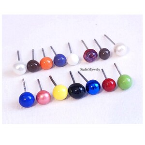 May include: Assortment of 14 colorful stud earrings with silver posts. The earrings feature a variety of colors, including white, brown, orange, blue, yellow, red, green, and black.