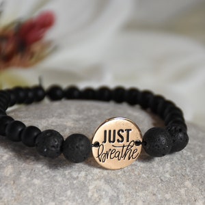 May include: Black lava rock beaded bracelet with a gold charm that says "JUST breathe".
