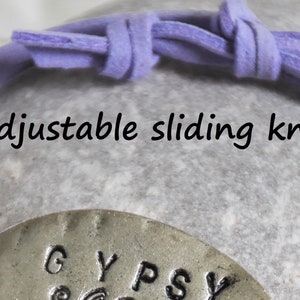 May include: A purple leather bracelet with an adjustable sliding knot and a silver charm that says "GYPSY".