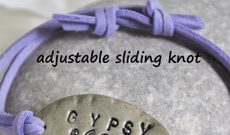 May include: A purple leather bracelet with an adjustable sliding knot and a silver charm that says "GYPSY".