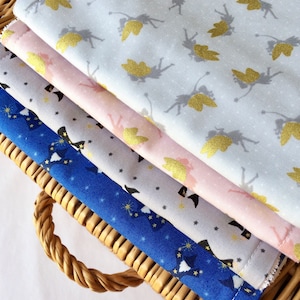 May include: Four fabric swatches stacked on top of each other. The top swatch is light blue with a gold glitter fairy pattern. The second swatch is pink with a gold glitter fairy pattern. The third swatch is gray with a gold glitter star pattern. The bottom swatch is blue with a black star and wand pattern.