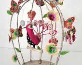 Textile sculpture, peacock in a birdcage with butterflies, flowers, mirror and bell. Embroidered, beaded bird, mixed media sculpture.