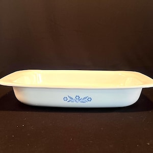 May include: A white rectangular baking dish with a blue floral design. The dish is made of ceramic and has a smooth, glossy finish.