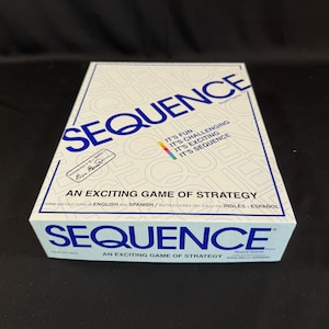 May include: A white box for the board game "Sequence" with blue text. The box reads "Sequence" in large letters, with the tagline "An Exciting Game of Strategy." Additional text includes "It's Fun, It's Challenging, It's Exciting, It's Sequence."