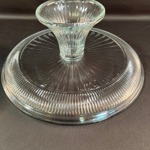 May include: A clear glass cake stand with a fluted edge and a pedestal base. The stand is designed for serving desserts or snacks.