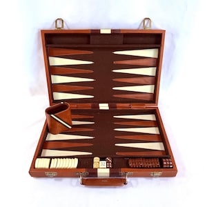 May include: Open brown leather backgammon set with a dark brown interior, featuring white and brown triangles. Includes dice, game pieces, and a dice cup. The set is designed with a handle and metal clasps for closure.