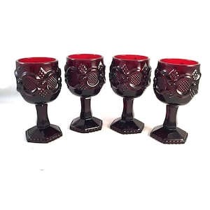 May include: Set of four ruby red glass goblets with a textured design. The goblets have a round bowl and a tall, slender stem.