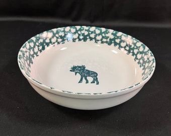 May include: A white ceramic bowl with a green and white speckled pattern around the rim. The bowl features a black silhouette of a moose in the center.