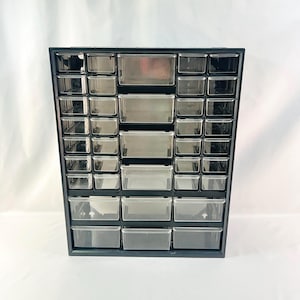 May include: Black plastic storage organizer with multiple clear drawers. The organizer has 36 drawers in total.