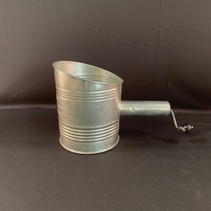 May include: A vintage silver metal flour sifter with a long handle and a black knob. The sifter has the text "The Turner Mfg. Co." printed on the side.