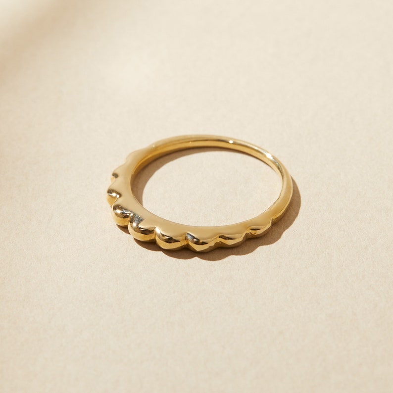 Puede incluir: Un anillo de oro con una banda texturizada y ondulada.