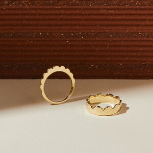Puede incluir: Dos anillos de oro con un dise&ntilde;o de borde festoneado. Los anillos est&aacute;n sobre una superficie blanca.