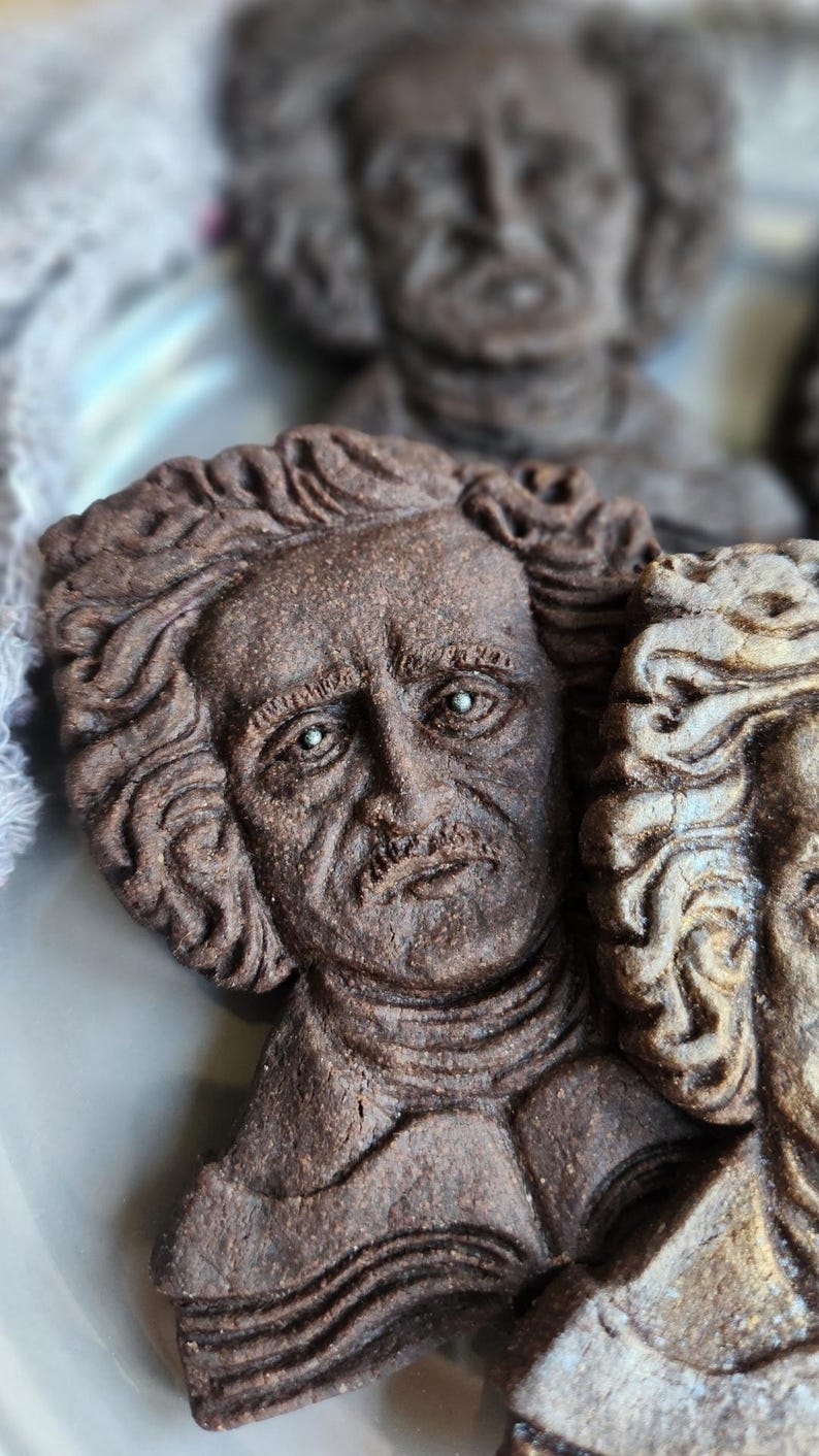 Puede incluir: Primer plano de una escultura marr&oacute;n detallada del rostro de un hombre con cabello rizado y bigote. La escultura tiene una superficie texturizada y probablemente est&aacute; hecha de un material denso. La imagen sugiere un busto o relieve.