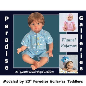 May include: A 20-inch vinyl toddler doll wearing blue pajamas with a moon and cloud pattern. The doll has brown hair and blue eyes. The image also shows other dolls and the text "Flannel Pajamas."