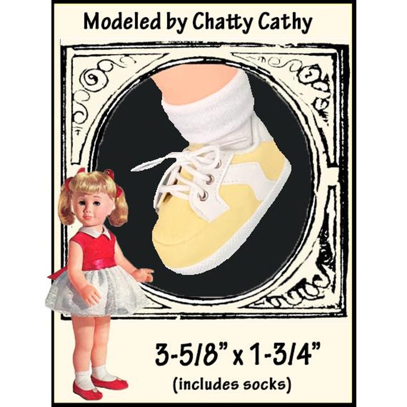 May include: A yellow and white lace-up sneaker with a white sole and white laces, worn with a white sock. The image includes the text Modeled by Chatty Cathy and dimensions of 3-5/8 inches by 1-3/4 inches, which includes the socks for the doll.