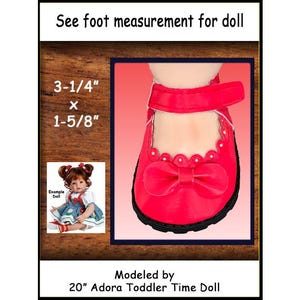 May include: A bright red doll shoe with a scalloped edge, a central bow, and a hook-and-loop strap. The text reads: See foot measurement for doll, 3-1/4" x 1-5/8", Example Doll, Modeled by 20" Adora Toddler Time Doll. The shoe has a black sole.
