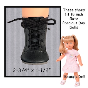 May include: Black doll boots with laces, measuring 2-3/4" x 1-1/2". The boots are designed to fit 18-inch Gotz Precious Day Dolls. The image includes an example doll wearing a pink dress and shoes.