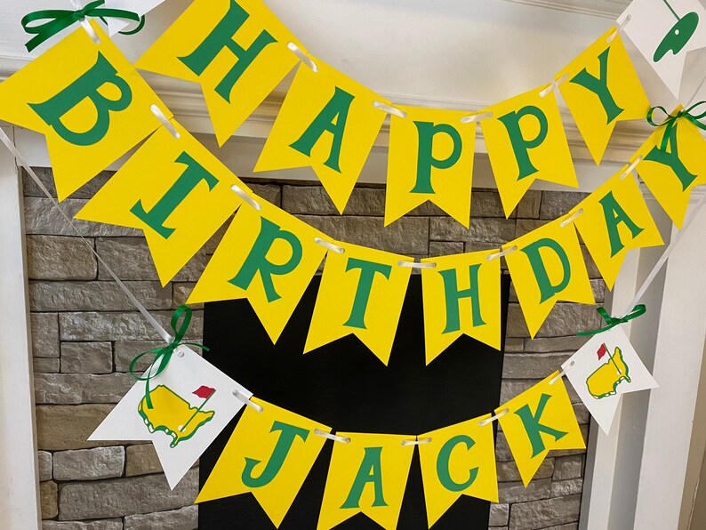 May include: A yellow and green banner with the words "Happy Birthday Jack" on it. The banner is decorated with green shamrocks and a small green and red golf flag.