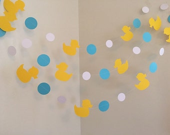 May include: A yellow and blue paper garland with duck silhouettes and circles. The garland is strung together with white thread.