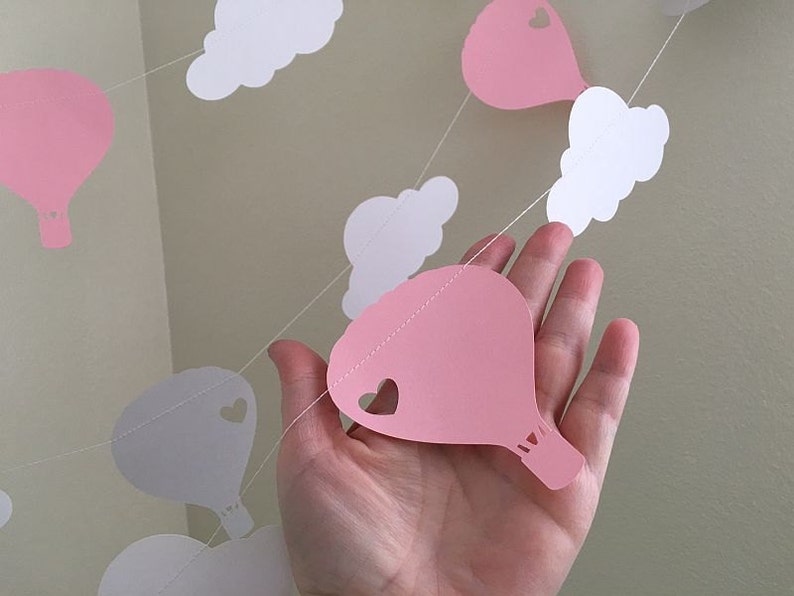 Puede incluir: Guirnalda de papel rosa y blanca con globos aerost&aacute;ticos y nubes. La guirnalda est&aacute; enhebrada con hilo blanco.