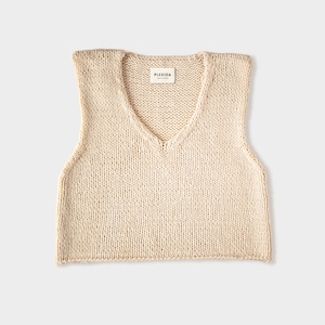 May include: A cream-colored knitted sleeveless vest with a V-neck. The vest has a small label that reads "PLEXIDA MADE IN DENMARK".