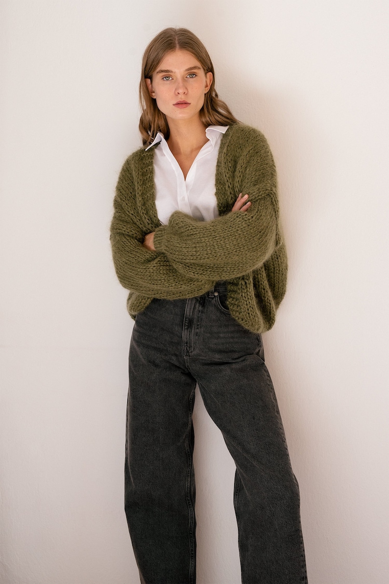Peut inclure: Une femme portant un cardigan en tricot vert sur une chemise blanche boutonn&eacute;e et un jean fonc&eacute;.