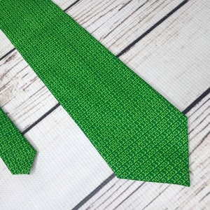 May include: A green tie with a pattern of yellow binary code.