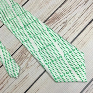 Tie front and end lay parallel angled into the corner of the frame. White tie with green bubbe letters looking identical to old scantron sheet used fr school testing.