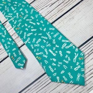 Peut inclure: Une cravate bleu turquoise avec un motif de chromosomes blancs.