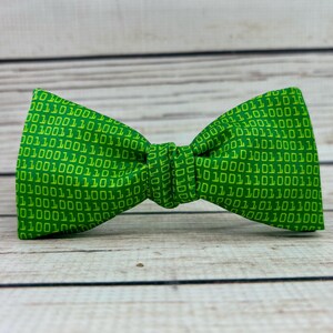 May include: A green bow tie with a pattern of yellow 1s and 0s.