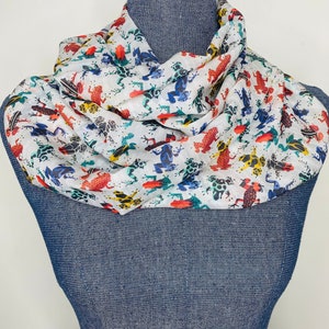 May include: White scarf with a colorful frog print. The frogs are red, yellow, blue, and green.
