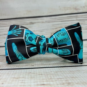 May include: A black bow tie with a blue and white pattern of x-ray images of bones.