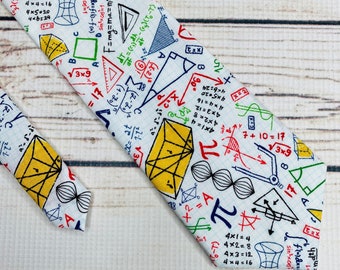 Puede incluir: Corbata blanca con un estampado de ecuaciones matemáticas coloridas, formas geométricas y símbolos. El diseño incluye fórmulas, triángulos y el símbolo pi. Un accesorio único para los amantes de las matemáticas.