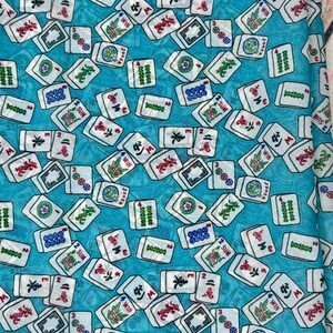 Op de afbeelding: Een turquoise blauwe stof met een herhalend patroon van witte mahjong-tegels. De tegels hebben verschillende Chinese karakters en symbolen, waaronder "WIN", "JOKER", "SUM" en "3".