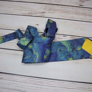 May include: A blue silk tie with a yellow lining. The tie features a print of Vincent van Gogh's "Starry Night" painting.