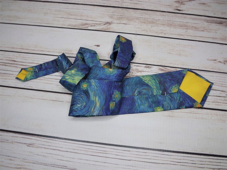 May include: A blue silk tie with a yellow lining. The tie features a print of Vincent van Gogh's "Starry Night" painting.
