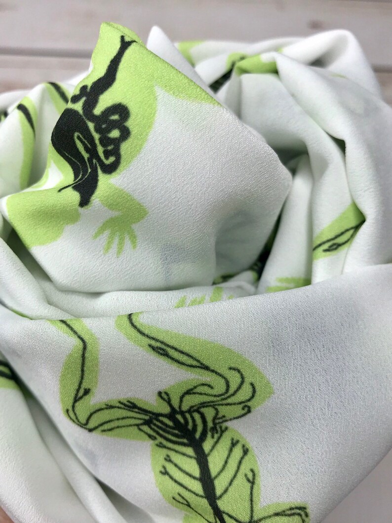 May include: White fabric with a green and black skeletal frog print. The fabric is soft and has a subtle sheen.