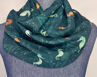 Lenço com estampa de cavalo-marinho, acessório inspirado no oceano, lenço infinito de chiffon, fundo azul-petróleo escuro.