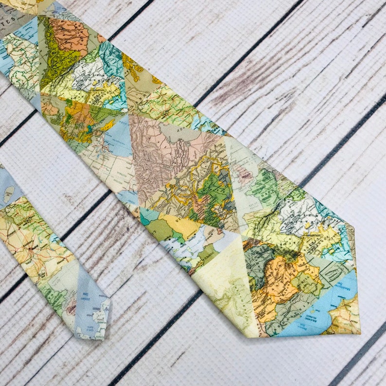 Tie front and end lay parallel angled into the corner of the frame. Triangle map pieces create a geometric collage or real-world maps. the colores of the maps range from green, tan cream blue, and mustard.