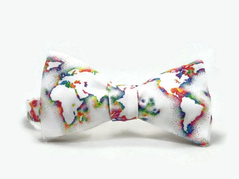 May include: A white bow tie with a colorful world map print. The map is outlined in white and filled with rainbow colors.