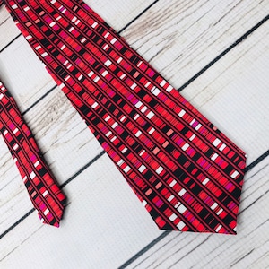 Peut inclure: Une cravate à motif géométrique rouge, noir, blanc et rose.