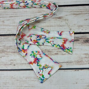 May include: A white bow tie with a colorful world map print. The map is outlined in rainbow colors and has a white background.