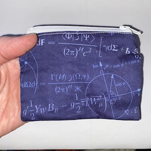 Könnte beinhalten: Eine blaue Reißverschlusstasche mit einem weißen Reißverschluss und einem weißen Rand. Die Tasche ist mit mathematischen Gleichungen und Symbolen bedeckt. Der Text auf der Tasche lautet: "dF = <Φ|Ψ>/(2π)hc^2∫dΣ + b ∂/∂Ω".