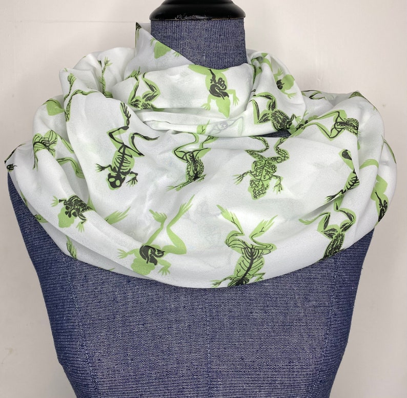 May include: White silk scarf with a green skeletal frog print.