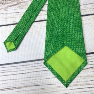 K&ouml;nnte beinhalten: Eine gr&uuml;ne Krawatte mit einem Muster aus wiederholtem Bin&auml;rcode, 1010101, in einem helleren Gr&uuml;nton.