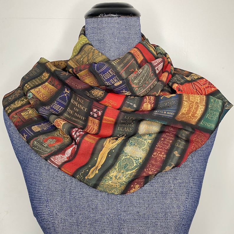 May include: A colorful scarf with a pattern of book spines. The scarf is made of a soft, lightweight fabric and features a variety of classic literary titles.